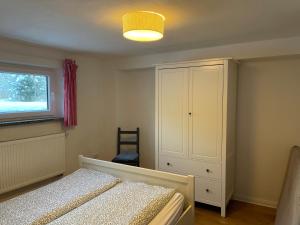 a bedroom with a bed and a cabinet and a window at Ferienwohnung am Waldrand mit Sauna in Biendorf