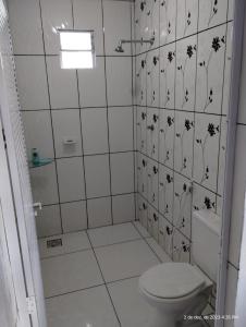 łazienka z toaletą i ścianą wyłożoną kafelkami w obiekcie Aconchego do bens w mieście Cruz