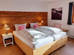 two beds in a bedroom with a wooden headboard at Ferienwohnungen Beargzit in Bad Hindelang