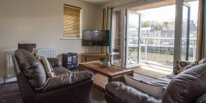 a living room with two leather chairs and a television at Riverside Apartments in Wick