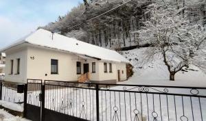 a house covered in snow with a fence at Rodinná chata v rekreačnej oblasti DRIENICA in Sabinov