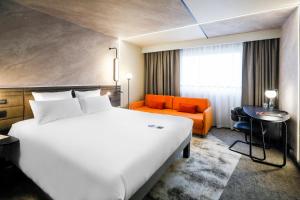 a hotel room with a large white bed and an orange couch at Novotel Warszawa Centrum in Warsaw