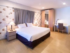 een slaapkamer met een groot bed en een bureau bij Crystal Resort Korat in Nakhon Ratchasima