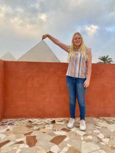 Eine Frau steht neben einer Mauer mit einer Pyramide. in der Unterkunft Energy Of Pyramid Hotel in Kairo