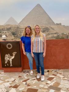 two girls are standing in front of the pyramids at Energy Of Pyramid Hotel in Cairo