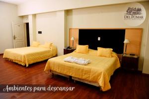 Habitación de hotel con 2 camas con sábanas amarillas en Del Pomar Hotel Boutique en Resistencia