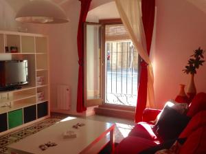 a living room with a red couch and a window at Apartamentos La Machacona Plaza de Santiago in Cáceres