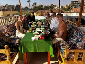 a group of people sitting around a table with food at Mikhaila Guest House in Luxor