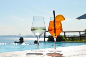 twee glazen wijn zittend op een tafel bij een zwembad bij Relais Villa Olivi in Costermano