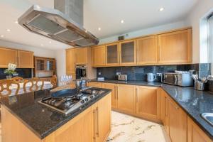 a kitchen with wooden cabinets and a stove top oven at Wembley Stadium 5 Bed House in Wembley