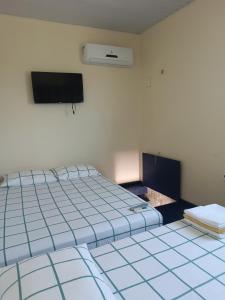 サリノポリスにあるKitnet no Farol Velhoのベッド2台、薄型テレビが備わる客室です。