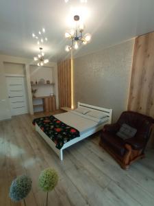 een slaapkamer met een bed en een stoel erin bij VIP apartment у центрі міста, новобудЖК Театральний,дуже простора in Rivne