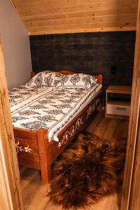 Una cama con marco de madera y un perro tirado debajo. en Domek Parzenica Nowy Targ en Nowy Targ