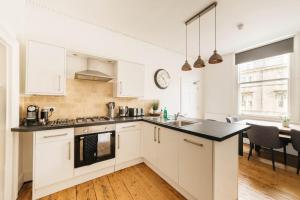 a kitchen with white cabinets and a black counter top at Central 4-bed House, 10 min Walk to Sights in Bath