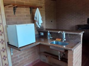 a kitchen with a sink and a refrigerator at Chalé Recanto Lobo Guará in Gonçalves