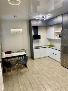 a kitchen with white cabinets and a table and chairs at Дуже файна квартира в самому центрі!!!!Переконайся!! in Rivne