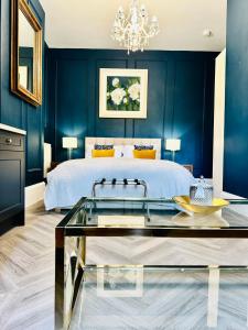 セント・ヘリア・ジャージーにあるEden Hotel - Beach Apartments & Suitesの青い壁のベッドルーム1室、ガラステーブル付きのベッド1台が備わります。