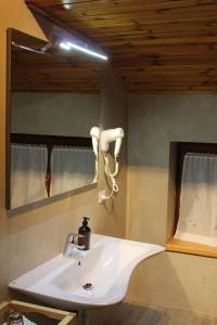 W łazience znajduje się biała umywalka i lustro. w obiekcie Cesa DOLOMITI w mieście Rocca Pietore