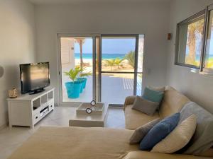 a living room with a couch and a tv and the ocean at Vila Mare - Praia de Chaves frontline in Cabeçadas