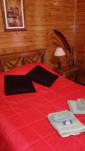 ein rotes Bett mit zwei Handtüchern und einer Lampe drauf in der Unterkunft Cabañas Brizas del Norte in San Ignacio