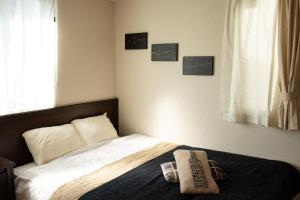 東京的住宿－Relax Lounge TOKYO，卧室内的一张床铺,墙上挂着照片
