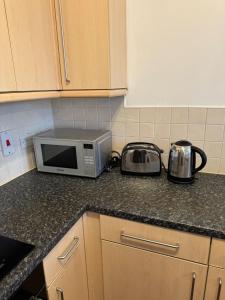 a kitchen counter with a microwave and pots and pans at Manchester Cosy flat close to City Centre and City stadium in Manchester