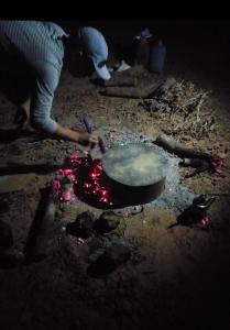 een vrouw die eten kookt in een pot op de grond bij النخلة in Erfoud