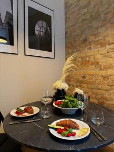 einen Tisch mit Teller mit Speisen und Weingläsern in der Unterkunft Stylish studio in the heart of Riga in Riga