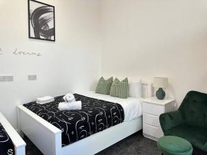 a bedroom with a bed and a green chair at Chic Downtown Flat in Dudley Near Attractions in Birmingham