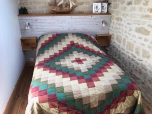 Bett in einem Zimmer mit einer bunten Decke in der Unterkunft La Lavande in Nuaillé-sur-Boutonne