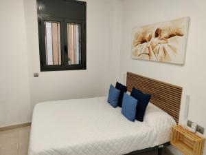 ein Schlafzimmer mit einem weißen Bett mit blauen Kissen in der Unterkunft Apartaments Puigcardener BX in Manresa