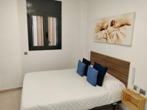 a bedroom with a white bed with blue pillows at Apartaments Puigcardener BX in Manresa