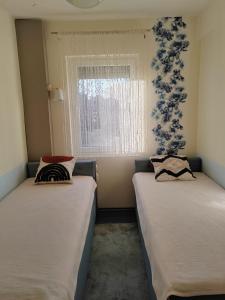 2 camas en una habitación pequeña con ventana en Apartman Stanimirović, en Zajecar
