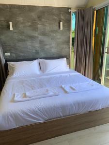 1 dormitorio con 1 cama con toallas en Baan Suan Madam บ้านสวนมาดามวังน้ำเขียว, en Wang Nam Khiao