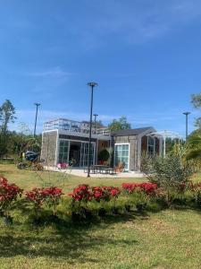 Baan Suan Madam บ้านสวนมาดามวังน้ำเขียว في وانغ نام خيو: منزل أمامه زهور حمراء