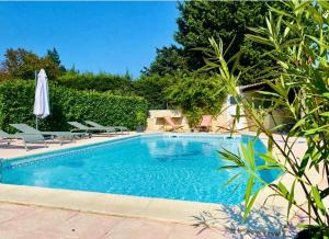 a swimming pool with chairs and an umbrella at La Maison Patricia in Aramon