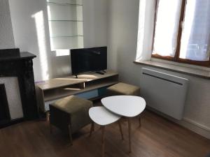 カルカソンヌにあるL'Ostalのデスク、テレビ、テーブル、椅子が備わる客室です。