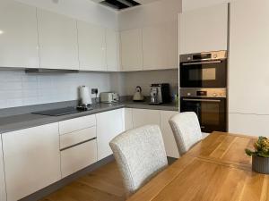 uma cozinha com armários brancos e uma mesa e cadeiras em Luxury one bedroom flat in Harrow em Harrow