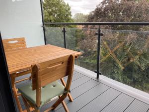 uma secretária de madeira e uma cadeira numa varanda com uma janela em Luxury one bedroom flat in Harrow em Harrow