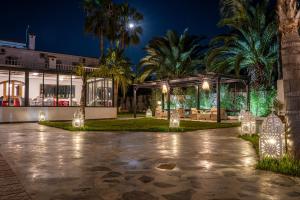 a night view of a building with palm trees and lights at Hôtel L'Hacienda in Rabat