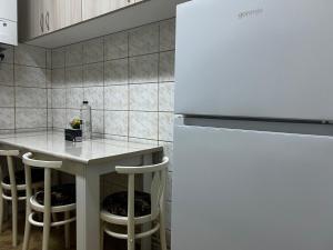 a kitchen with a white refrigerator and a table with stools at AradVest Studio in Arad
