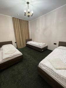 3 Betten in einem Zimmer mit Kronleuchter in der Unterkunft Tourkomplex Karpaty in Slawske