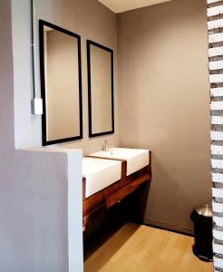 a bathroom with a white sink and two mirrors at La Malila Hostel in Udon Thani