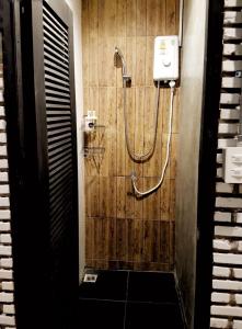 a shower in a bathroom with a wooden wall at La Malila Hostel in Udon Thani