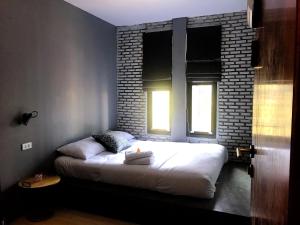 a bed in a room with a brick wall at La Malila Hostel in Udon Thani