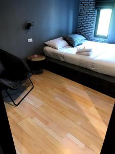 a bedroom with a bed and a chair and a wooden floor at La Malila Hostel in Udon Thani