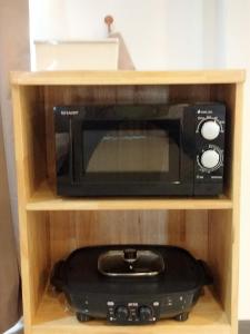 a black microwave on a wooden shelf with a black appliance at Habor House by Koh Larn Riviera in Ko Larn