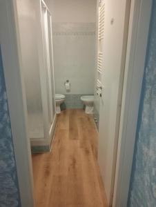 een kleine badkamer met 2 toiletten en een houten vloer bij Albergo Belvedere in Albissola Marina