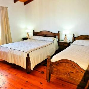 2 Betten in einem Schlafzimmer mit Holzböden und 2 Lampen in der Unterkunft Amancay in Villa Elisa