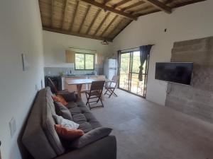 sala de estar con sofá marrón y cocina en Morada da Laika, en Praia do Rosa